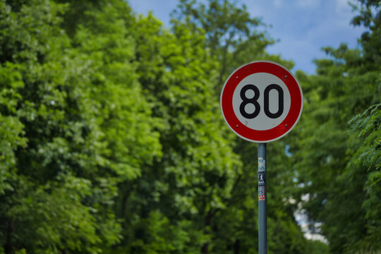 German 80 Speed Limit Traffic Sign with Lush Green Forest Trees in the Background