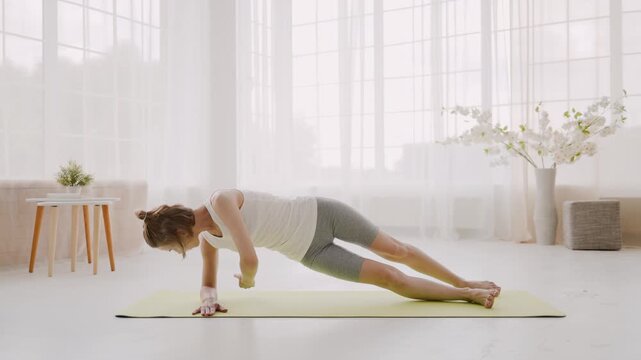 Woman doing side plank with twisting on yoga mat at home