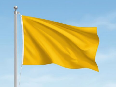 A bright yellow flag waving on a metal pole against a clear blue sky during a sunny day
