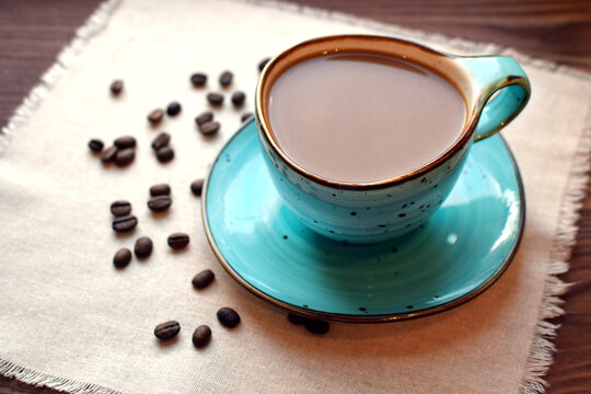 Coffee with milk in a beautiful blue ceramic cup on a wooden table. Cup of coffee, coffee beans.