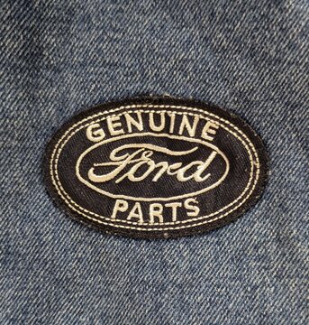 Vista de cerca del estampado del logotipo de la marca Ford y el texto Genuine Parts, en una chaqueta de tela vaquera. Madrid, Espa&ntilde;a, 21 de mayo de 2026