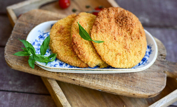 Crispy  deep fried   chicken  burgers . Breaded  with cornflakes chicken  breast fillets  with  french fires and fresh    aragula on wooden rustic background