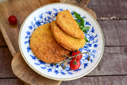 Crispy  deep fried   chicken  burgers . Breaded  with cornflakes chicken  breast fillets  with  french fires and fresh    aragula on wooden rustic background