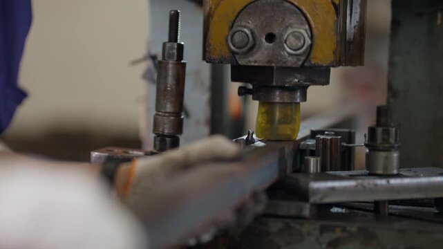 Worker adjusts metal mold with gloved hands. Machine hovers above coins ready for pressing. Tooling shows industrial precision in a factory. Scene captures manufacturing focus and craftsmanship