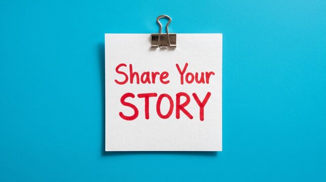 Share Your Story handwritten message on white note, motivational text on paper with binder clip, storytelling concept on blue background