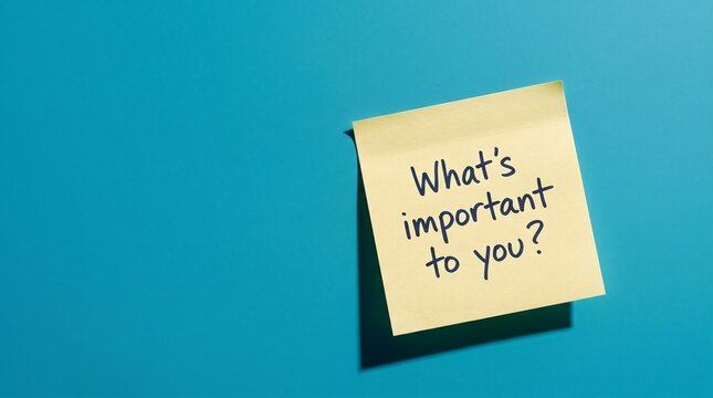 Yellow sticky note with handwritten text What's important to you, conceptual message on blue background, business priority and values reminder