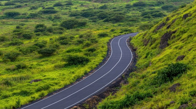 A winding road traversing lush green hills under a clear sky, showcasing nature's beauty