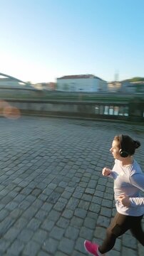 Caucasian woman runs along the embankment. Unusual view, filmed on FPV drone. 