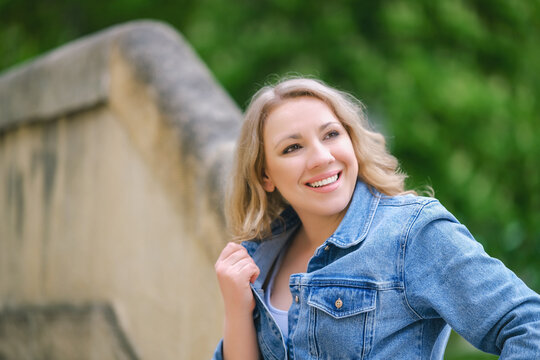 Cheerful attractive female smiling and looking away outdoors. Concept of happiness, positive emotions and outdoor recreation.