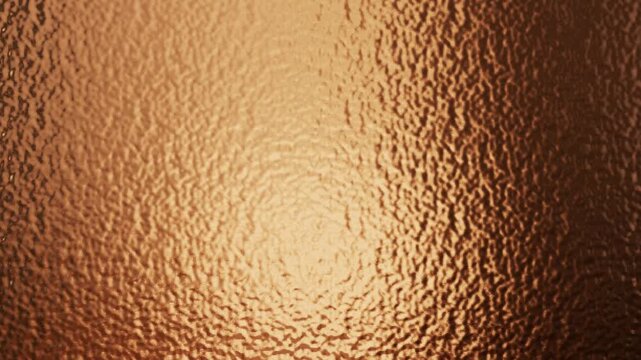 Warm bronze metallic texture with rippled surface and soft golden light reflections for background