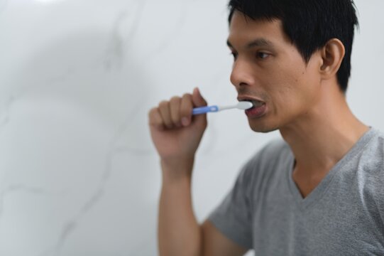 Man Brushing Teeth in Bathroom with Focus on Daily Hygiene Routine