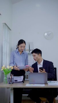 Two business women are sitting and talking in the office and discussing projects on laptops and graphs working together in the office.