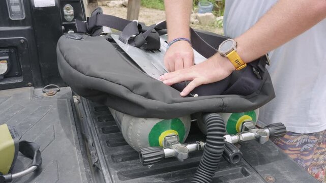 Male scuba diver preparing and assembling his double tank sidemount equipment on a truck bed