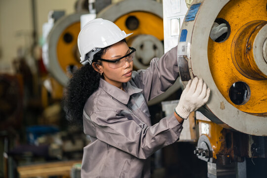 Female Engineer Inspecting Flywheel Of Industrial Punch Press In Metalworking Factory