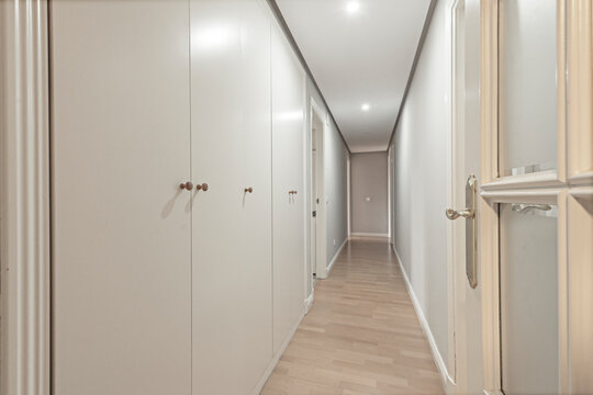 White sliding and hinged doors with a frosted transom window leading to a bedroom with light wood floors.