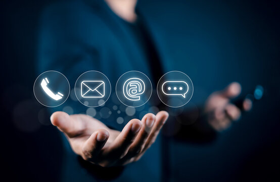 Businessman holding virtual contact us icons including phone, email, address, and chat message. Concept of customer support, communication channels, business inquiry, and service network.