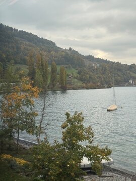 Small sailboat moored on calm shore of Lake Thun in Leissigen during autumn