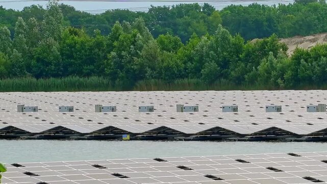 Floating solar panel farm generating renewable energy on a lake with green forest in the background on a sunny day