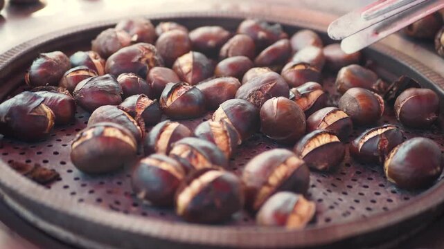 Close up of roasted chestnuts being prepared and served on a metal tray
