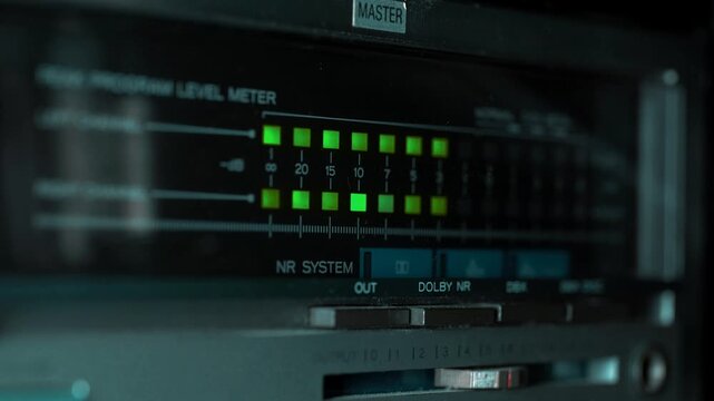 Close up of audio level meter led lights bouncing on vintage cassette deck equipment. Sound volume indicator VU meter loop for music production, studio, retro audio recording, DJ mix.