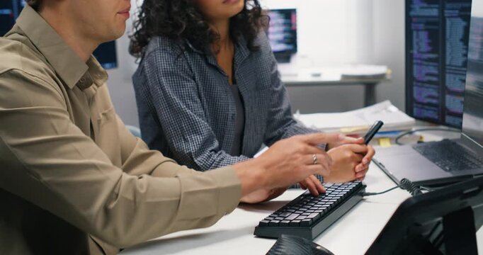 Close-up shot of wo developers cooperate on software architecture review server integration and mobile interfaces exchanging ideas on performance security and product strategy.

