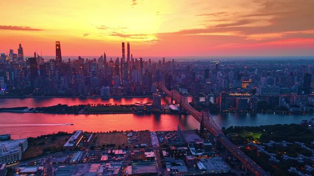 Motor boat moves by the East River waterscape colored pink by setting sun. Footage over New York City along the Queensboro Bridge.