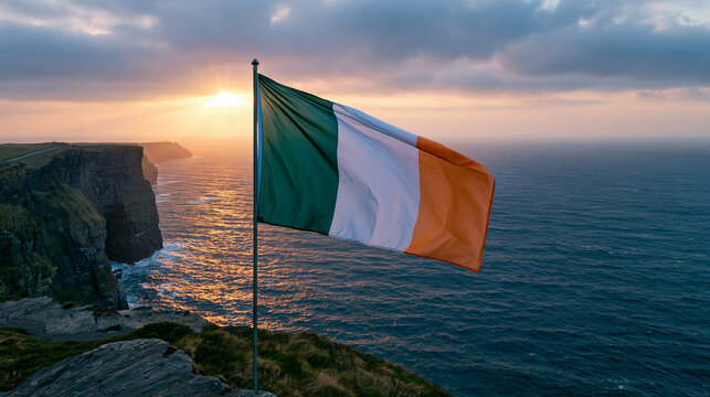 Irish flag flying proudly over dramatic sea cliffs during golden hour sunset.