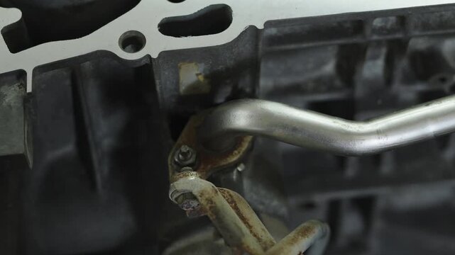 Metal coolant pipe attached with bracket to car engine block.