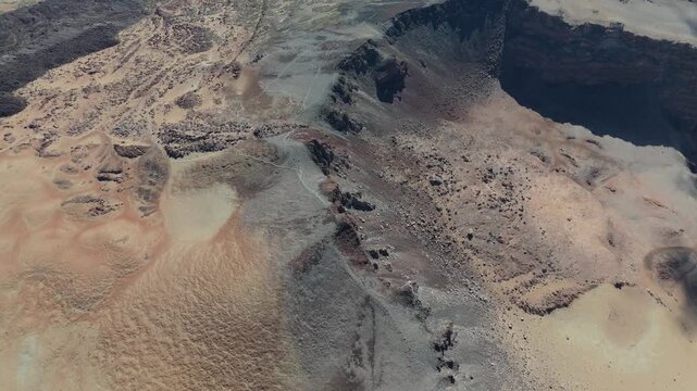An aerial drone push in shot captures the vast, rugged volcanic landscape around Pico Viejo on Tenerife, Canary Islands. Desert-like terrain with rocky formations and winding paths.