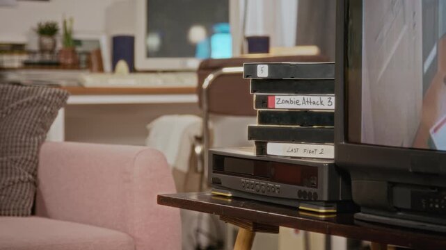 VHS tapes stacked on VCR player next to retro CRT television playing vintage footage. Perfect for nostalgic marketing campaigns and retro technology documentaries
