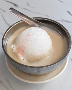 A bowl of shaved ice dessert also known as "Jagung Susu" in Sarawak, served in a sweet milky broth with a spoon.