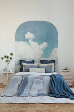 Inviting bedroom interior with a cloud wall mural and cozy blue and white bedding, perfect for a serene retreat