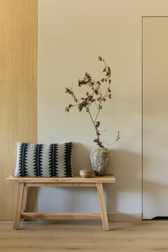 Minimalist Entryway Bench with Decorative Pillow and Vase Against Neutral Wall and Wood Panel