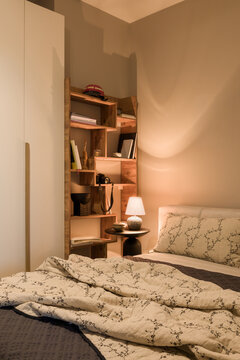 Cozy Bedroom Corner with Wooden Shelf, Bed, and Warm Lighting for Relaxing Home Interior