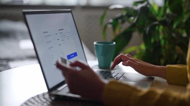 Woman paying online using credit card and laptop at home.