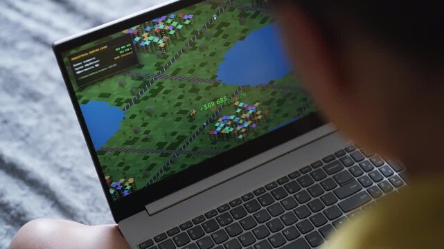 Woman playing economic strategy game on laptop.