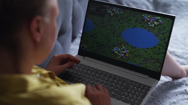 Woman playing economic strategy game on laptop.