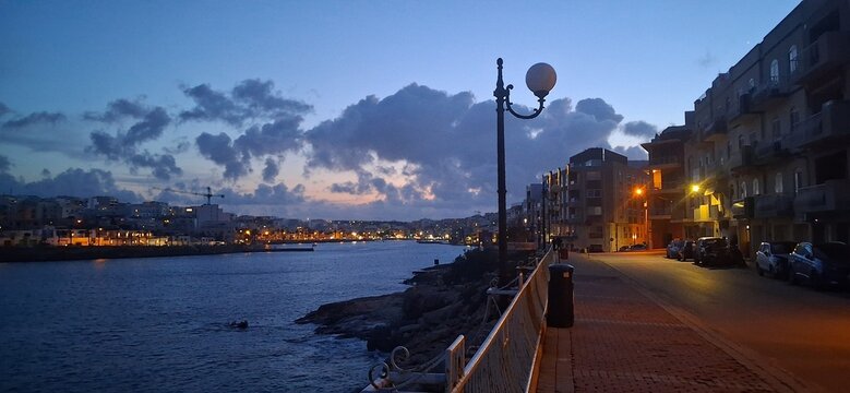 Coastal Waterfront at Sunset with Dramatic Clouds and Calm Sea
