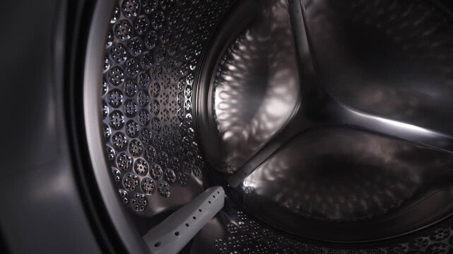 Empty stainless steel washing machine drum inside view close up.