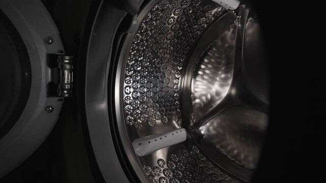Empty stainless steel washing machine drum inside view close up.