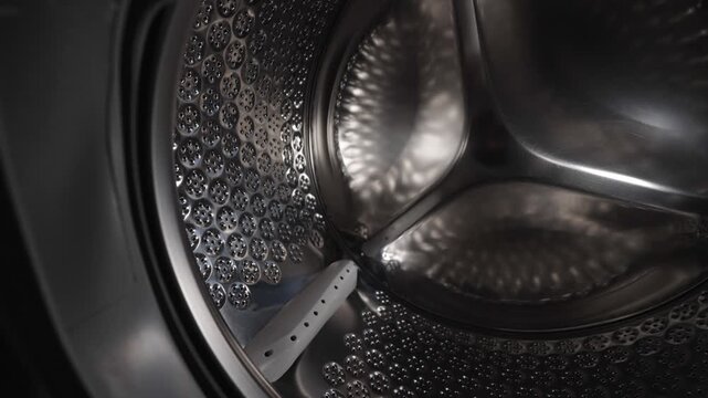 Empty stainless steel washing machine drum inside view close up.