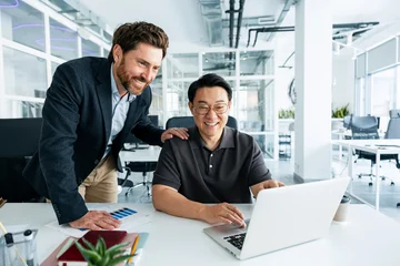 Business people collaborating on laptop in modern office © Maria Vitkovska