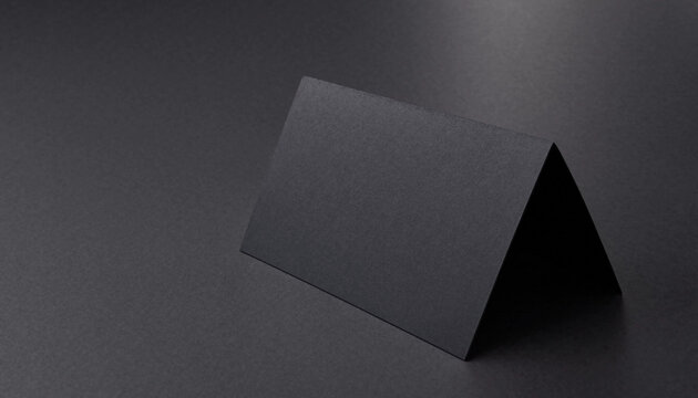 Blank folded black paper card standing on a dark background for modern stationery mockup with paper product stationery template invitation greeting minimalist cardstock presentation