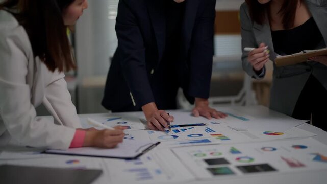 Professional business team analyzing financial data charts and graphs during a corporate meeting while brainstorming project strategies for market growth and development