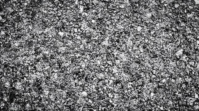 A close-up view of a rough asphalt road surface with small grey and black stones creating a textured ground pattern in black and white