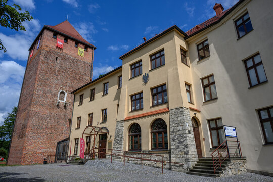 Oswiecim Castle with its medieval Gothic brick tower decorated with eagle banners on a sunny day, Oswiecim, Poland