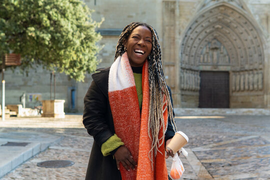 Woman laughing on city street while eating a healthy lunch