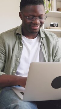 Smiling african american man typing on laptop