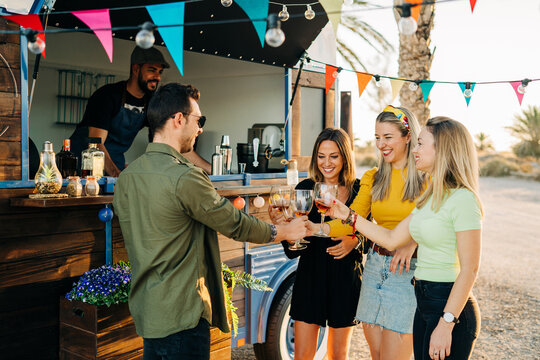 Joyful friends toasting with glasses near food truck