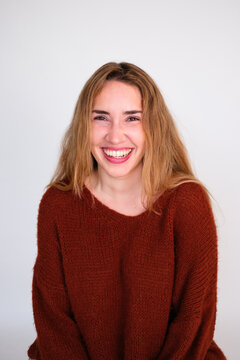 Woman Smiles and Sits Against a White Background in Casual Setting